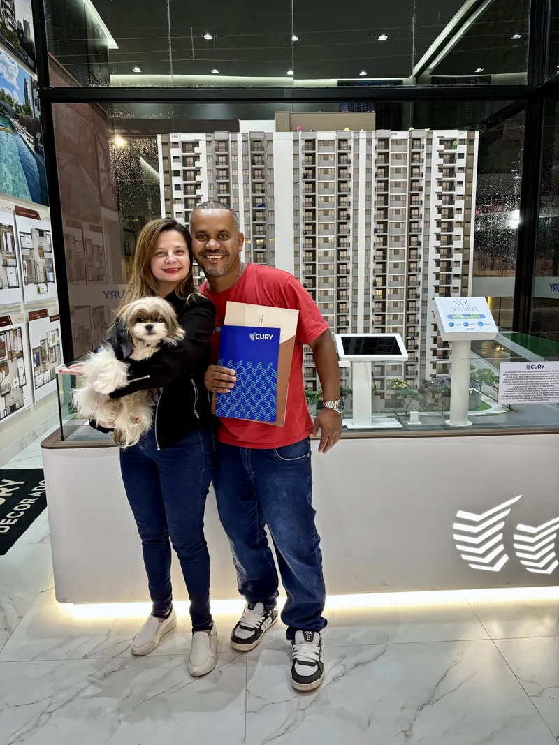 Pessoas em estande imobiliário com maquete ao fundo
